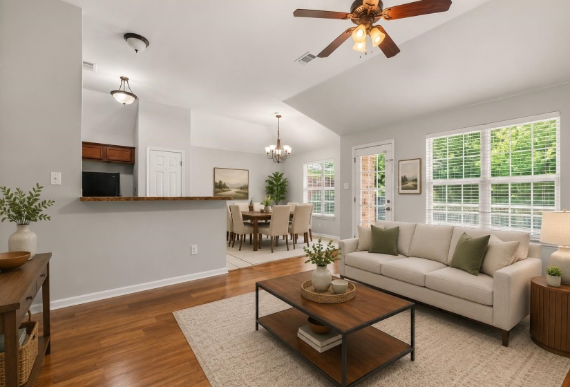 Living area featuring hardwood flooring, vaulted ceiling, and ample natural light through multiple windows