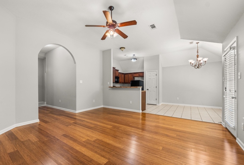 Living area featuring wood-finish flooring, an arched doorway, and a ceiling fan with integrated lighting