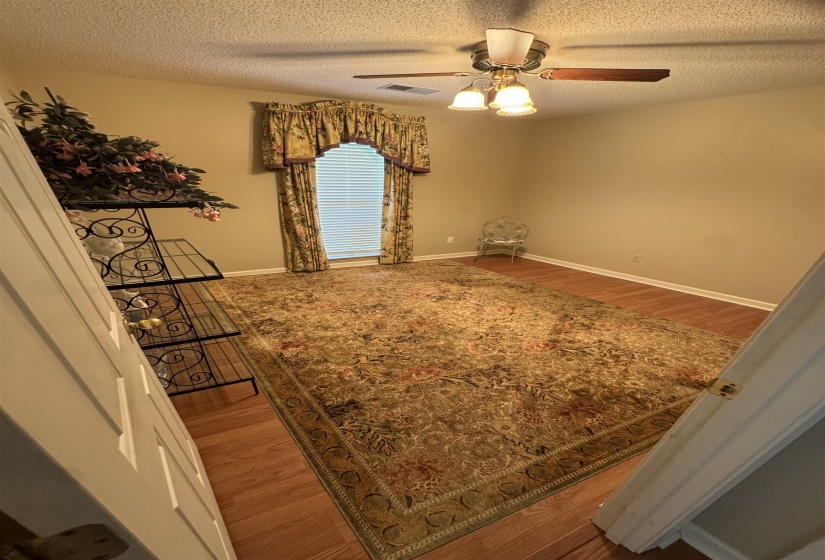 Room featuring wood-finish flooring, a window with blinds and valance, a ceiling fan with integrated lighting, and neutral wall tones