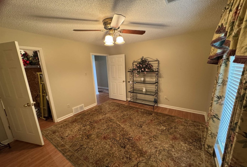 Room featuring wood-finish flooring, a ceiling fan with integrated lighting, and a window with blinds