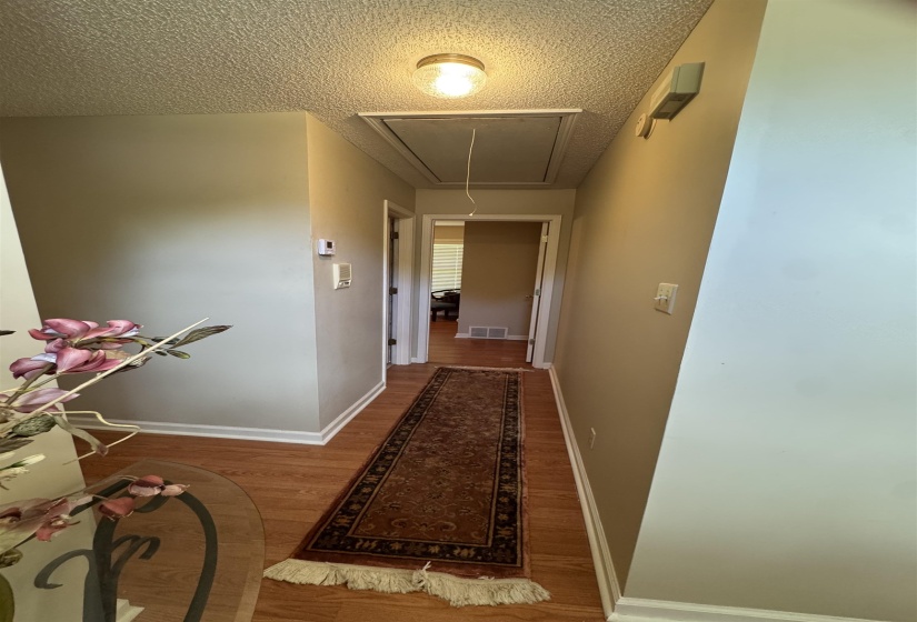 Hallway with wood-finish flooring, neutral wall paint, and white baseboards