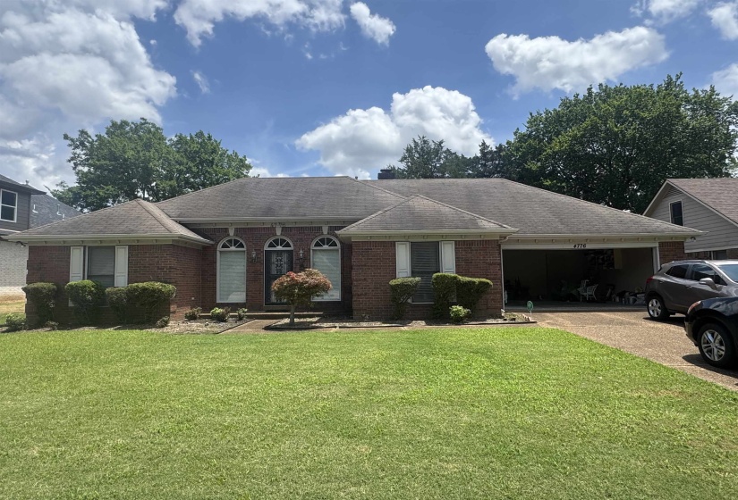 Brick exterior featuring a two-car garage, arched entryways, and shuttered windows
