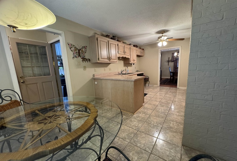 Kitchen space featuring light wood-finish cabinetry, a sink with faucet, and tile flooring