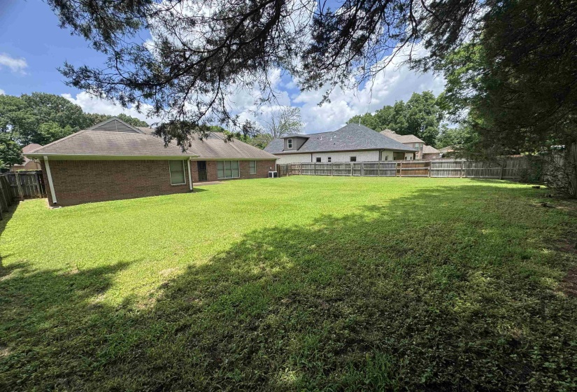Expansive green lawn with a privacy fence bordering the property