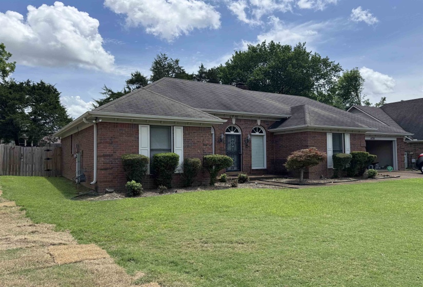 Brick exterior residence featuring a dark shingle roof and white window shutters
