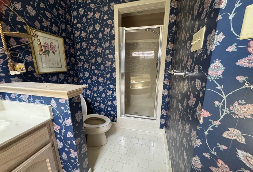 Bathroom with patterned wall covering, white tile flooring, and a glass-enclosed shower
