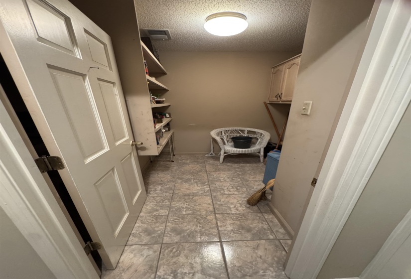 Utility room featuring tiled flooring, a built-in shelving unit, overhead cabinetry, and a ceiling-mounted light fixture