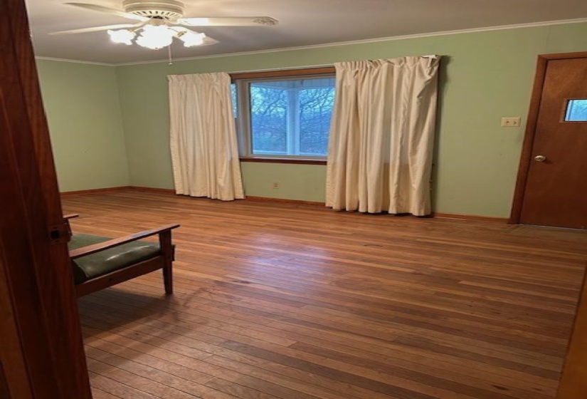 Empty room featuring ornamental molding, wood-type flooring, and ceiling fan