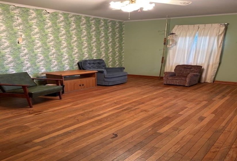 Sitting room with ornamental molding, wood-type flooring, and a ceiling fan