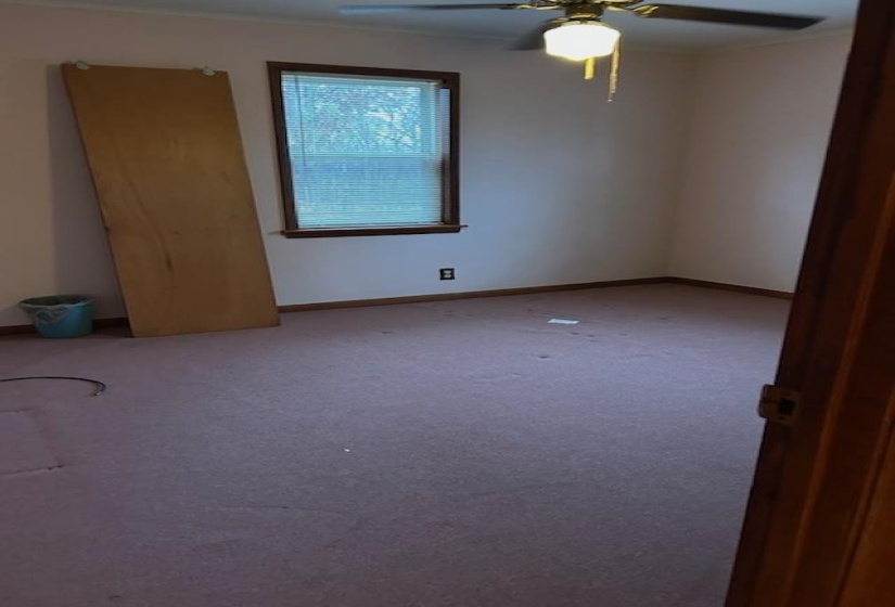 Carpeted empty room with baseboards and a ceiling fan