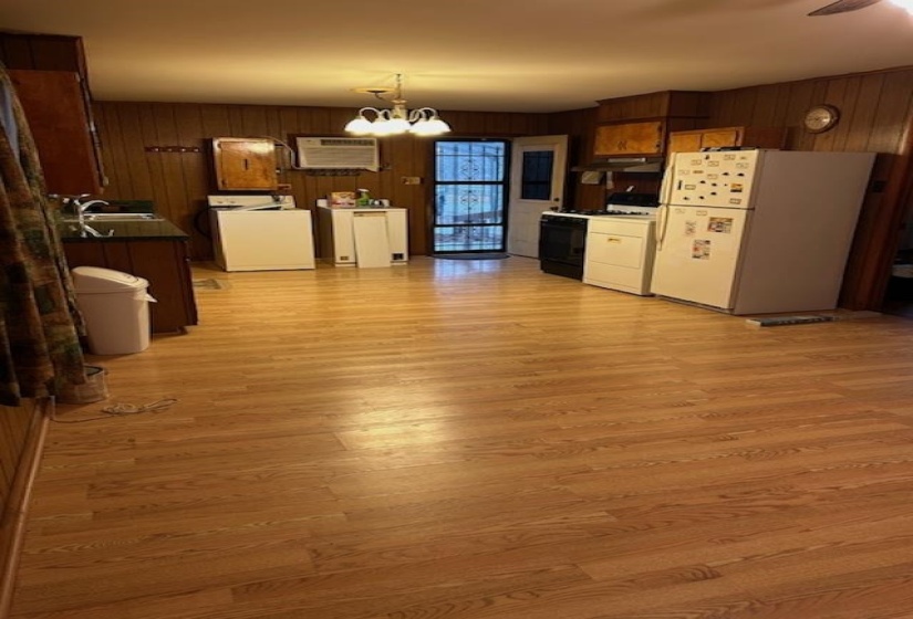 Kitchen featuring freestanding refrigerator, washer / clothes dryer, gas stove, wooden walls, and a chandelier