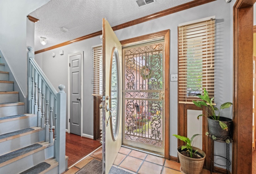 Entryway featuring an ornate security door, a paneled main door with an oval window, and terra cotta tile flooring