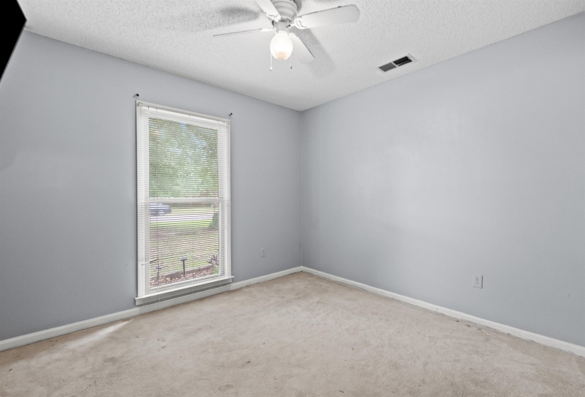 Interior room with light gray walls, textured ceiling, and light-colored carpet flooring