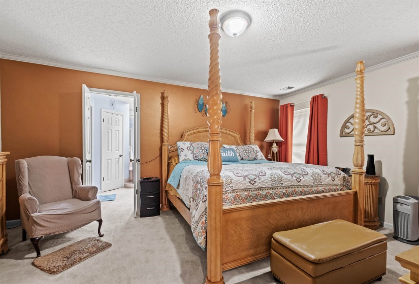 Bedroom featuring neutral carpeting, a painted accent wall, and white trim