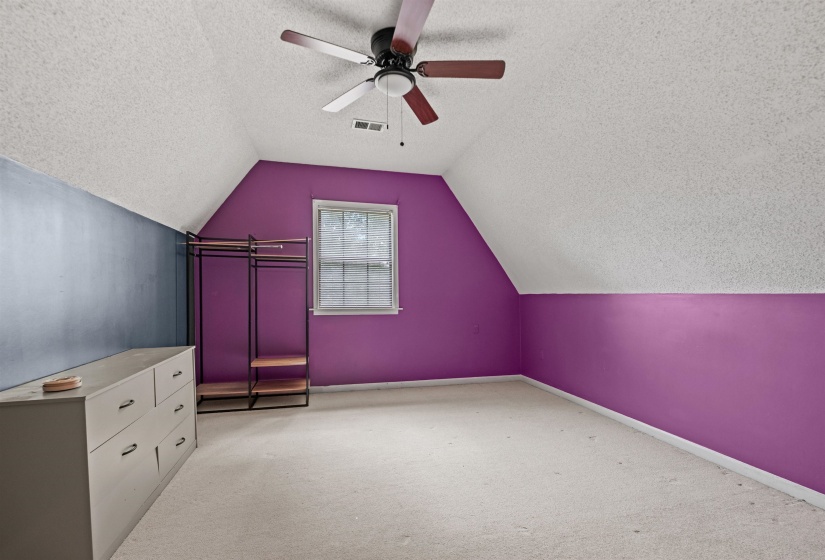 Carpeted room with sloped ceilings, a window, and a ceiling fan