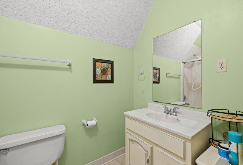 Bathroom with a single vanity featuring a white countertop and base cabinetry, a wall-mounted mirror, and a toilet