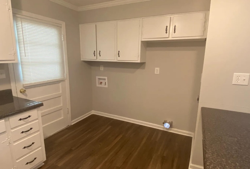 Laundry area featuring wood-finish flooring and upper cabinetry
