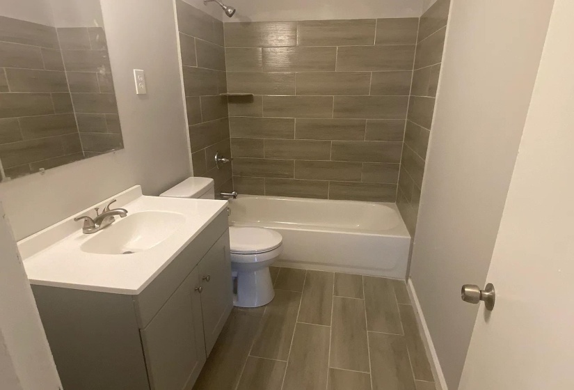 Bathroom featuring a white vanity with integrated sink, chrome faucet, and rectangular mirror