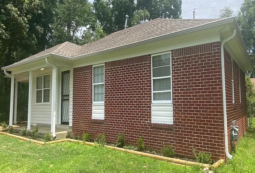 Brick exterior featuring white siding accents and a covered front porch