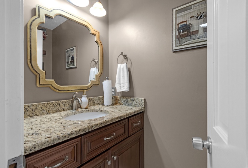 Vanity area featuring a granite-style countertop, integrated sink, and dark wood cabinetry with chrome hardware