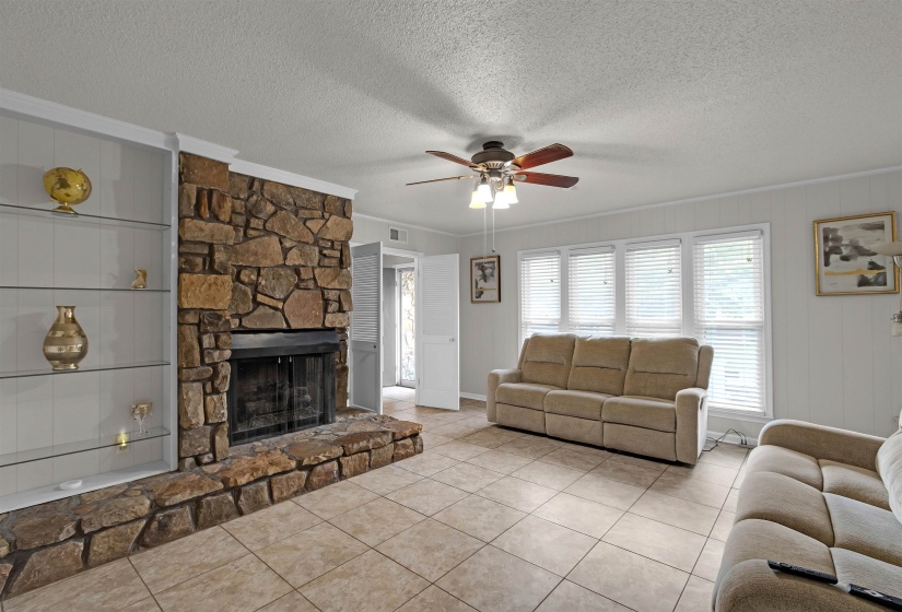 Stone-clad fireplace with hearth and built-in shelving