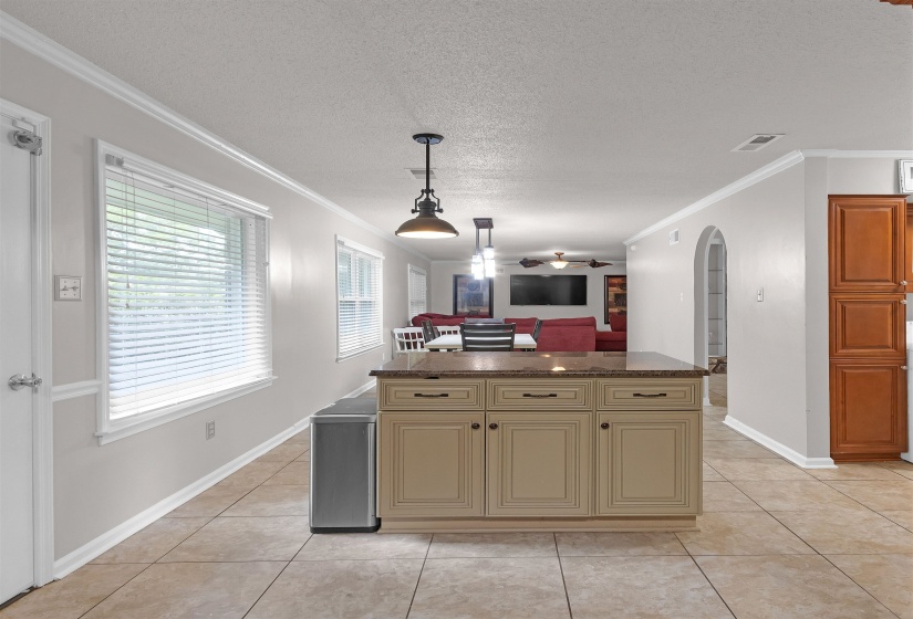 Kitchen island featuring a stone-finish countertop, beige cabinetry, and black hardware