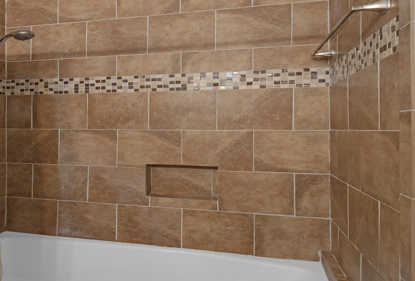 Bathroom featuring a tiled shower surround with a decorative mosaic accent band