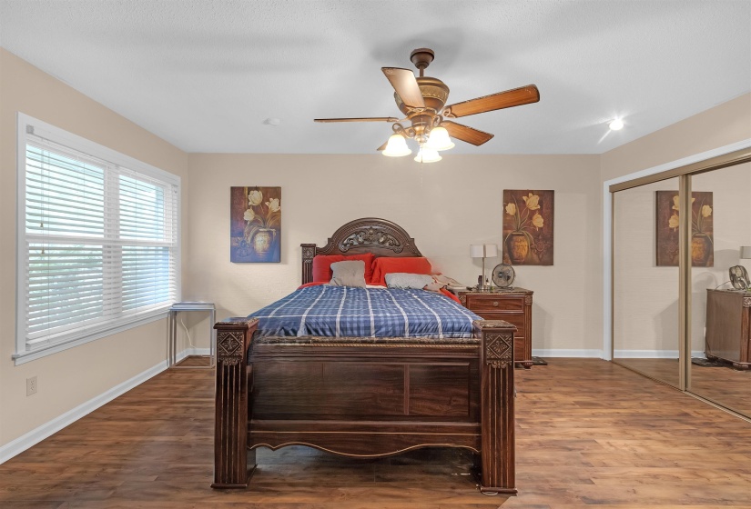 Bedroom featuring wood-finish flooring, two large windows with blinds, a ceiling fan with integrated lighting, recessed lighting, and mirrored closet doors