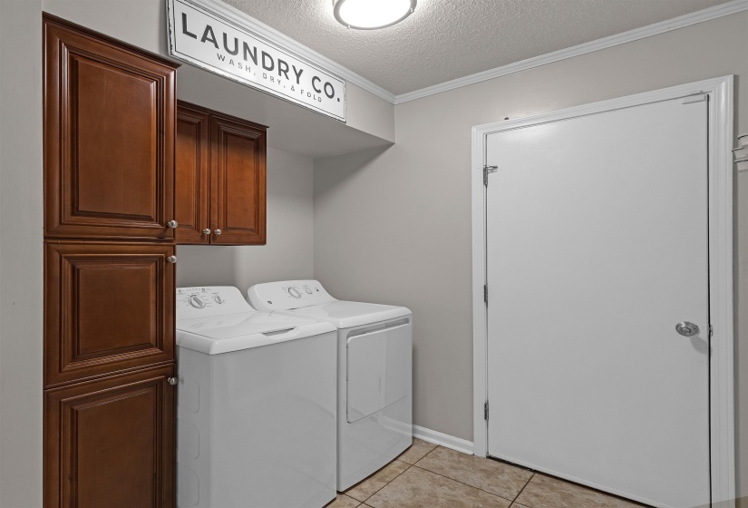 Laundry area featuring a side-by-side washer and dryer, tile flooring, and cabinetry with a rich wood finish