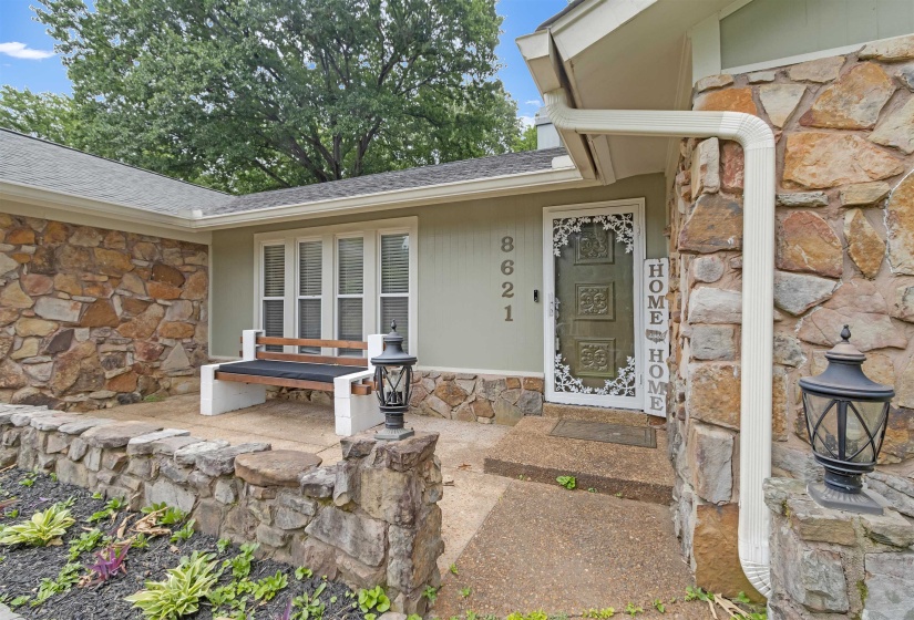Stone facade residence featuring a covered entry