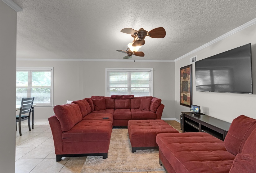 Spacious living area featuring light gray walls and crown molding