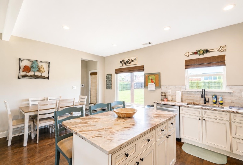 Kitchen featuring a large island with stone countertop, white cabinetry with dark hardware, stainless steel dishwasher, and a black faucet