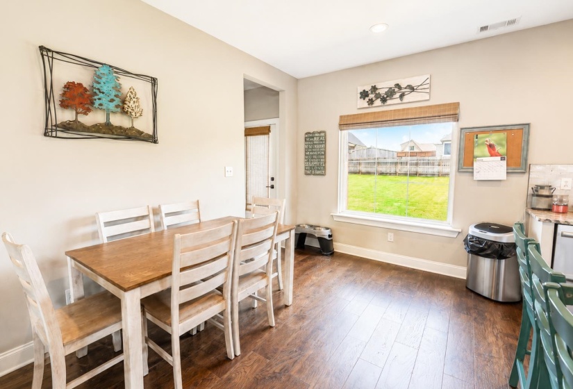 Expansive dining area featuring wood-finish flooring and a large window overlooking a fenced yard