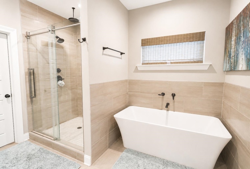 Freestanding soaking tub with matte black fixtures, set against a tiled wall