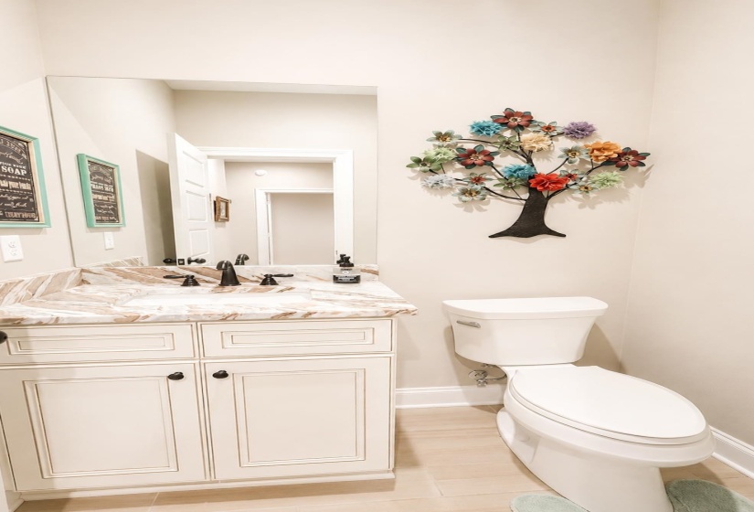 White vanity with brown-veined countertop, undermount sink, and dark bronze fixtures