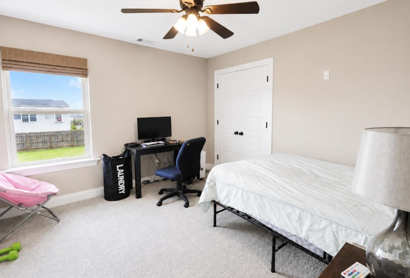 Carpeted room featuring a ceiling fan with light fixture, a large window, and a white paneled door with black hardware