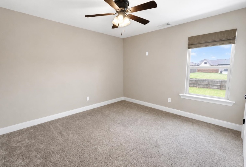 Carpeted interior space featuring neutral wall tones, white baseboards, and a ceiling fan with integrated lighting