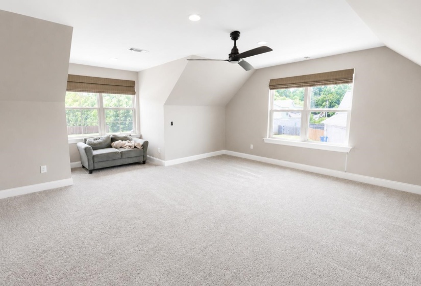 Expansive room featuring light gray carpeting, neutral wall tones, and white trim
