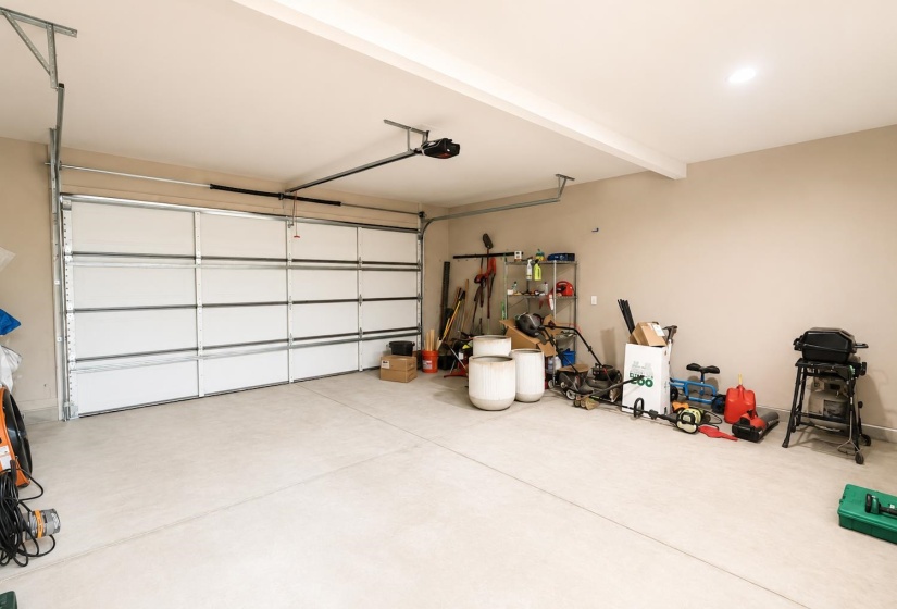 Spacious garage featuring a sectional overhead door with an automatic opener, a concrete floor, and painted walls
