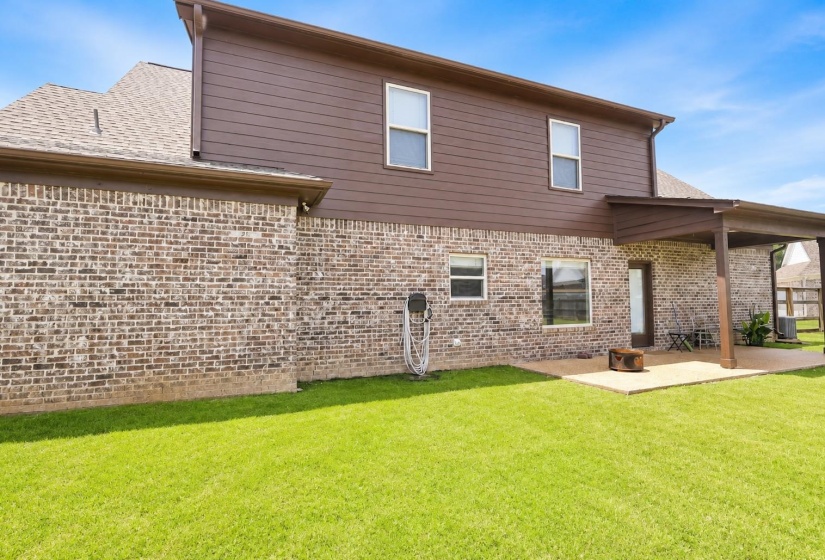 Expansive green lawn with a covered patio area and concrete slab