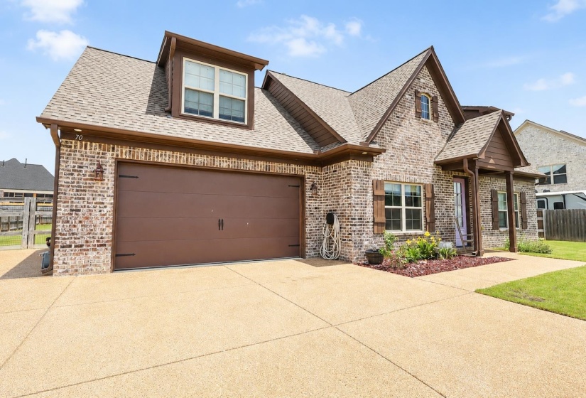 Brick exterior with dormer window, coordinating brown garage door, and a covered front porch entry