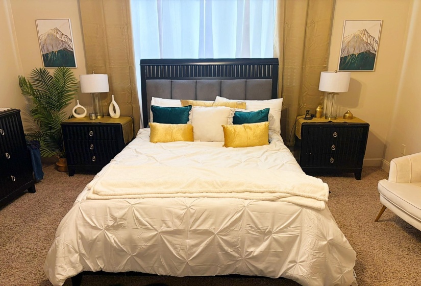 Bedroom featuring a dark wood bed frame with a padded headboard, dual dark wood nightstands with drawers, and carpeted flooring