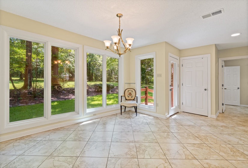 Room with expansive window wall, light-toned tile flooring, and a brass-finish chandelier