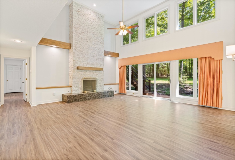 Spacious interior with vaulted ceilings, wood-finish flooring, and a floor-to-ceiling stone-clad fireplace