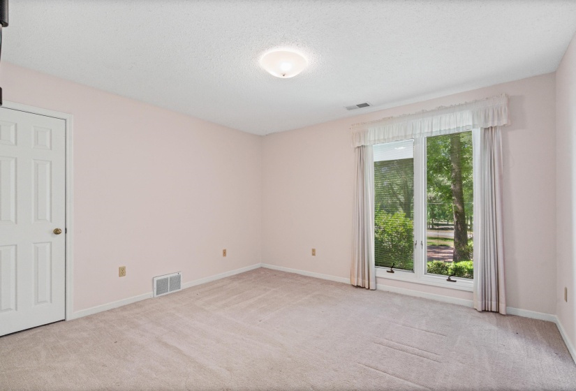 Room featuring neutral wall-to-wall carpeting, a multi-pane window with drapery, a six-panel interior door, and a flush-mount ceiling light fixture