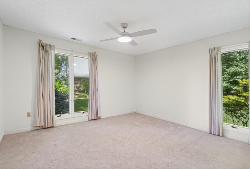 Spacious room featuring carpeting, white walls, and a ceiling fan