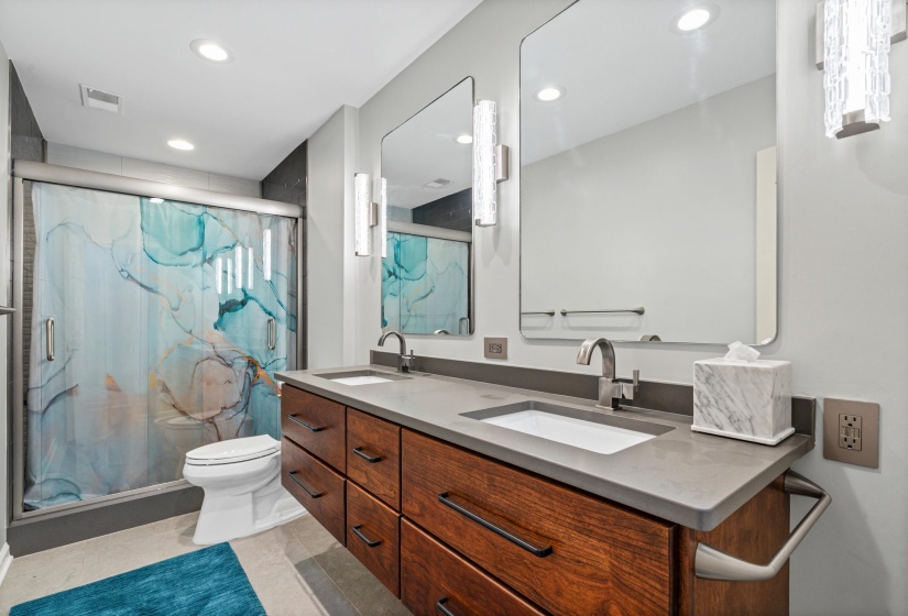Contemporary bathroom featuring a dual vanity with a concrete-finish countertop, wood-finish cabinetry, and undermount sinks