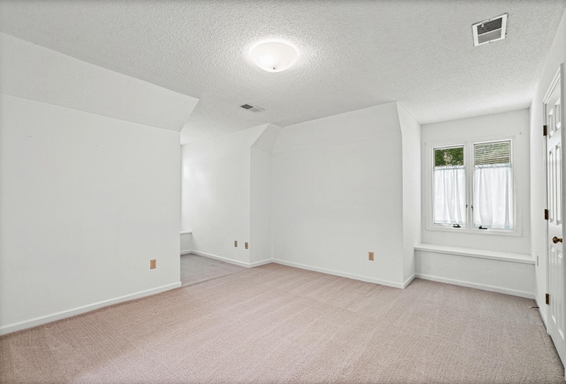 Carpeted bonus room with a window seat, white walls, and a recessed ceiling light