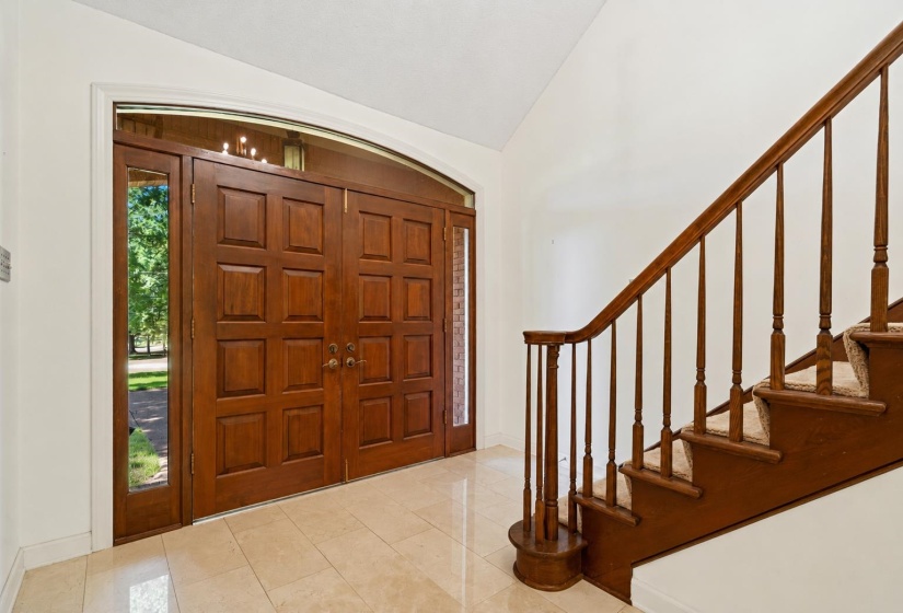 Double wood-paneled entry doors with sidelights and an arched transom window