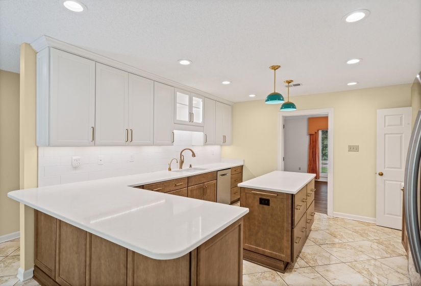 Kitchen featuring two-tone cabinetry with white upper and wood-finish lower cabinets, solid surface countertops, a center island with drawer storage, and recessed lighting